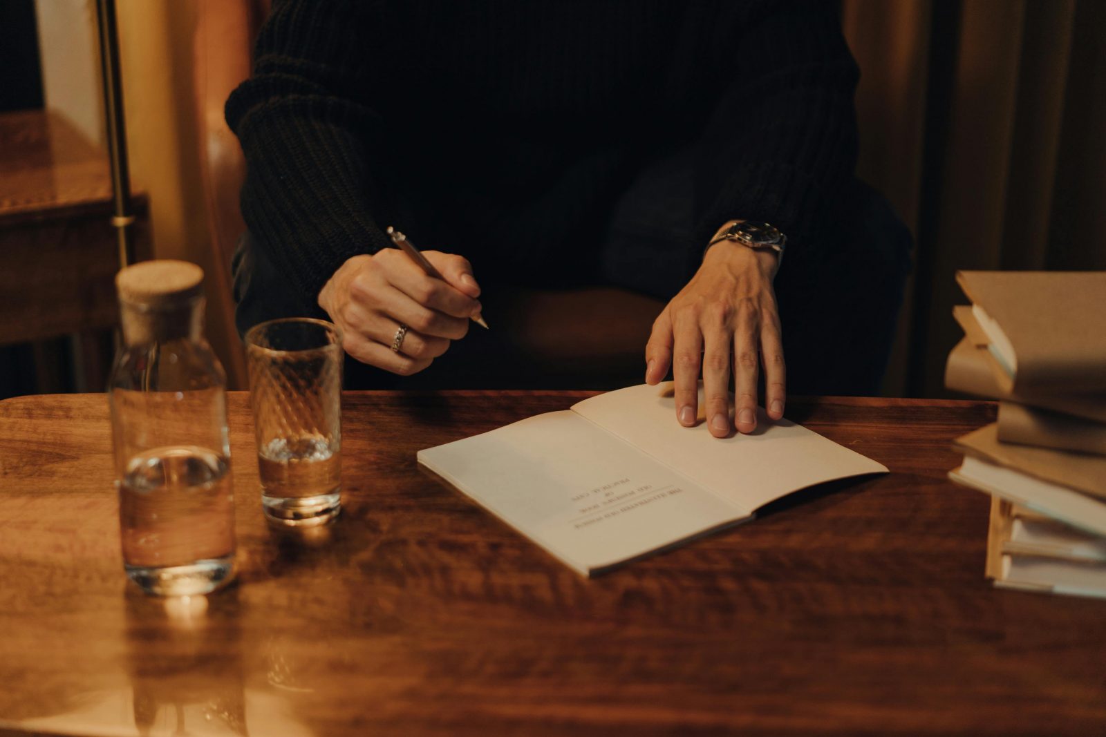 auteur sur un bureau en bois type avec un verre d'eau qui écrit des notes sur un carnet