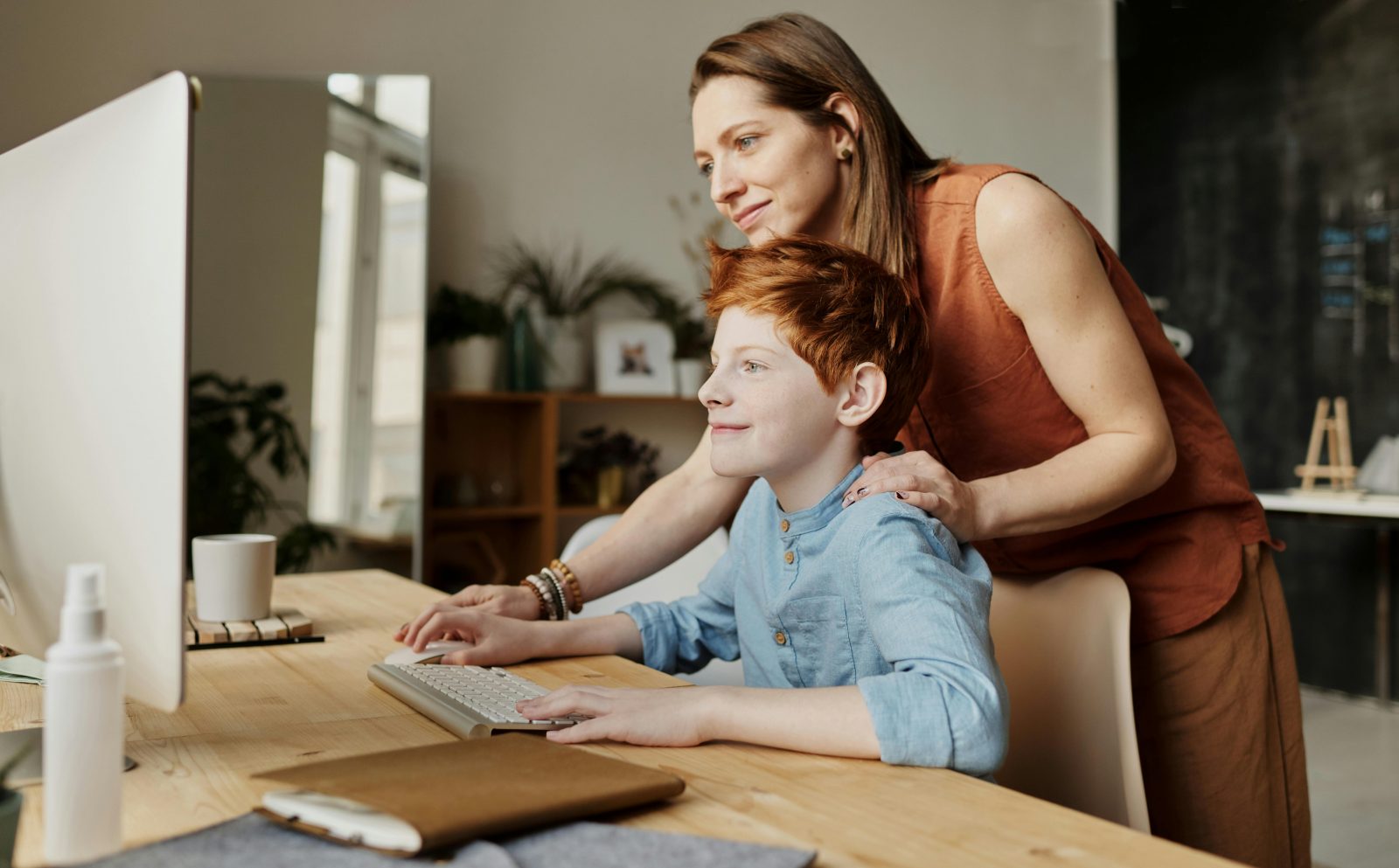 enfant dys roux qui travaille à la maison sur son bureau avec une femme